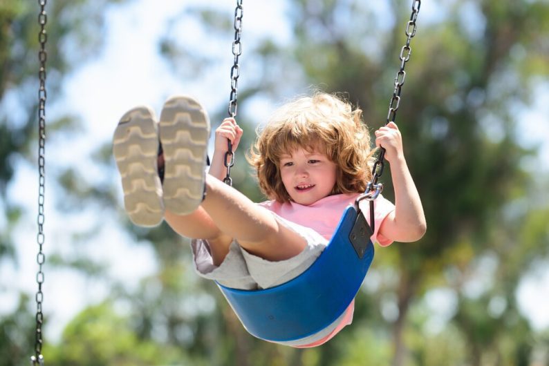 criança se divertindo em balanço em playground infantil